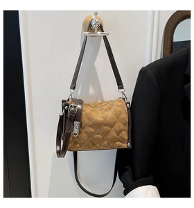 Detailed macro view of brown suede quilted crossbody bag with metal lock hardware