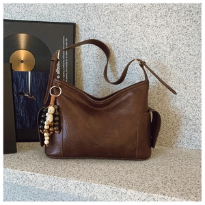 Details der dunkelbraunen Vintage-Achseltasche mit Ethno-Perlen und Ledertextur
