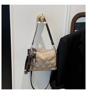 Detail of beige quilted mini bag with brown patent leather straps and silver hardware