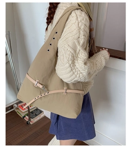 Detail of khaki nylon tote bag with metal eyelets and decorative thin leather buckle strap