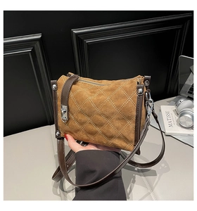 Detail of brown quilted faux suede handbag with silver twist lock and stitching