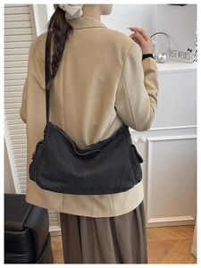 Back view of model wearing a black washed denim crossbody bag with side pockets and strap
