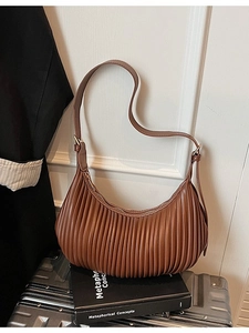 Brown pleated vintage shoulder bag with adjustable strap and metal zipper on luggage