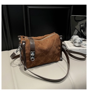 Detail of brown suede crossbody bag with diamond stitching and silver metal clasp