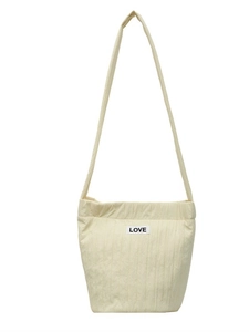 Minimalist cream vertical quilted shoulder bag with LOVE patch on white background