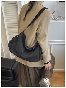 Detail of wide shoulder strap and white stitching on a black denim hobo bag for women