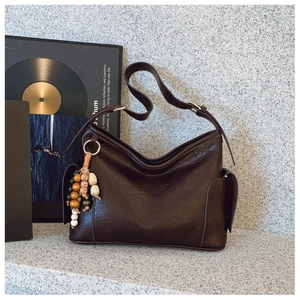 Detailansicht der braunen Vintage-Achseltasche mit Boho-Anhänger und Markenlogo-Detail