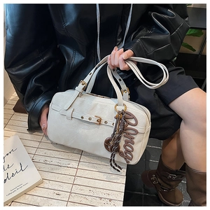 Close-up of cream Boston bag featuring retro cracked texture and golden hardware details