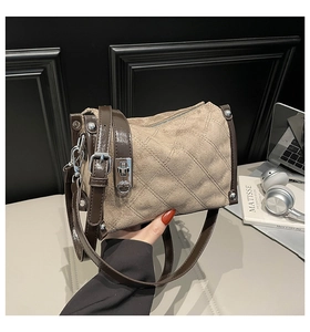 Detail of khaki suede quilted handbag featuring brown leather trim and silver hardware