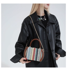 Detail of colorful woven handbag with brown leather trim, studs and gold chain strap
