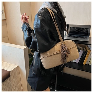 Detail of light beige underarm bag with decorative Bingo letter charm and stylish buckle