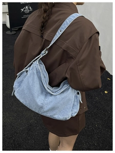 Close-up of light blue washed denim hobo bag with adjustable eyelet shoulder strap
