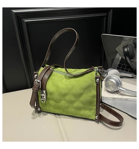 Detail of green quilted crossbody bag with adjustable brown strap and silver buckles