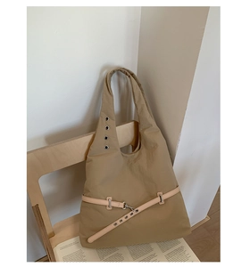Detail of khaki tote bag with metal eyelets and leather strap on a stylish wooden chair