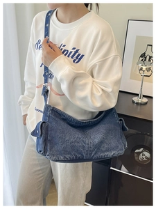 Detail view of denim crossbody bag showing side flap pockets and metal eyelet adjustment