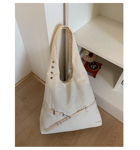 Detail of beige large tote bag featuring silver rivets and modern buckle decoration