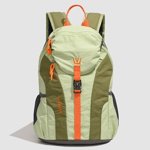 Close-up of lightweight nylon backpack showing green color-block design and orange accents
