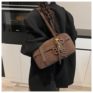 Close-up of vintage brown shoulder bag with wax leather texture and decorative charms