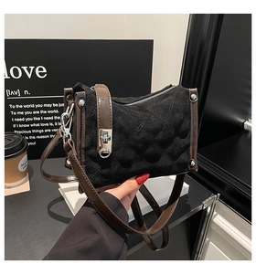 Detail of black suede crossbody bag with brown patent leather straps and silver metal lock
