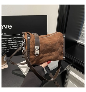 Detail of brown suede crossbody bag with classic quilted pattern and silver lock closure