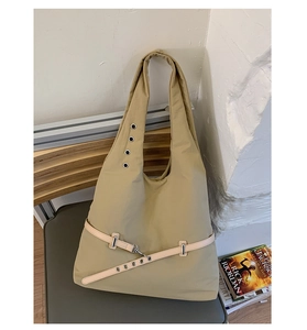 Detail of khaki nylon tote bag with metal eyelet strap and utility buckle accents
