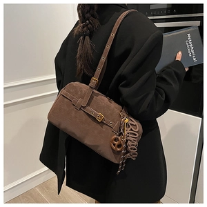 Brown suede shoulder bag detail with buckle strap and creative pretzel pendant