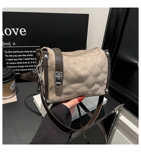 Detail of beige suede crossbody bag with brown faux leather trim and silver rivets