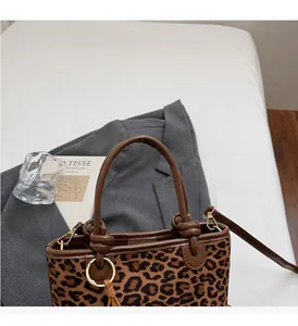 Détail du sac seau à imprimé léopard avec poignée en cuir marron et anneaux dorés