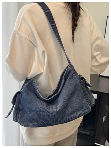 Detail of blue denim crossbody bag with wide shoulder strap and flap side pocket