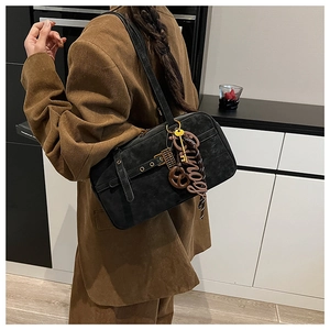 Detail view of black suede shoulder bag with pretzel charm and golden key accessories