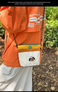 Dettaglio della borsa a tracolla in nylon color-block con ricamo di cane cartone animato