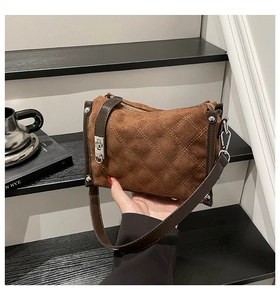 Detail of brown suede handbag with yellow diamond stitching and silver metal hardware