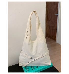 Detail of off-white hobo bag showing metal eyelets and decorative buckle strap