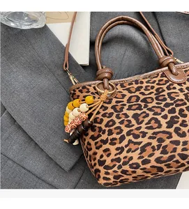 Détail du sac seau imprimé léopard avec poignée en cuir et breloque à pampilles perlées