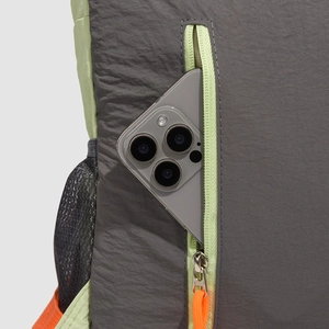 Close-up of grey nylon backpack pocket with neon zipper and smartphone for scale