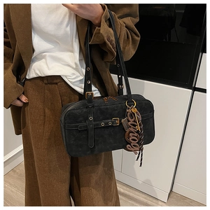 Detailed macro view of black suede shoulder bag featuring adjustable strap and gold hardware