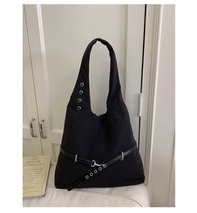 Detail of black canvas tote bag with metal eyelets and decorative leather strap