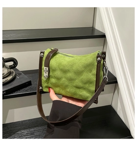 Detail view of bright green quilted shoulder bag with suede texture and silver buckle