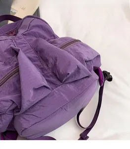 Detail of purple ripstop nylon backpack fabric showing texture and zippered outdoor compartments