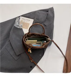 Détail de l'intérieur du sac seau marron tressé montrant un espace de rangement spacieux