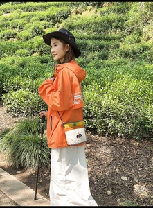 Dettaglio stile outdoor della borsa a tracolla in nylon a contrasto e giacca a vento arancione