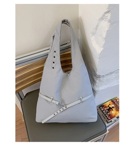 Detailed close-up of light gray tote bag featuring metal eyelets and industrial buckle