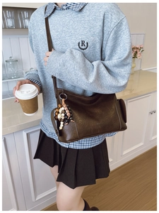 Detail einer dunkelbraunen matten Ledertasche mit buntem Perlenanhänger im Vintage-Stil