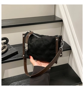 Detail of black suede crossbody bag with diamond quilting and brown leather strap