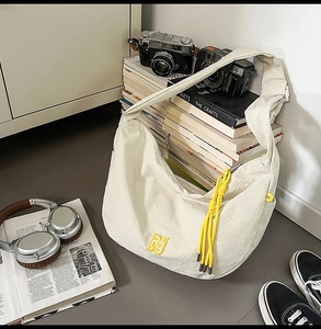 Detail of off-white grid nylon hobo bag with yellow RJ embroidery and rope charm