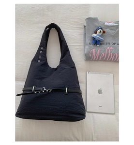 Detail of black pleated tote bag with metal buckles and leather trim accents
