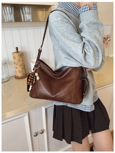 Detailansicht einer dunkelbraunen Hobo-Tasche mit einem einzigartigen Perlenanhänger
