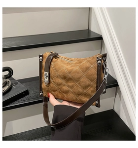 Close-up of brown suede crossbody bag with white diamond quilting and silver rivet details