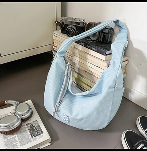 Close-up of light blue nylon crossbody bag with micro-check texture and logo embroidery