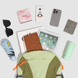 Knolling view of color-block backpack with various travel essentials on grey background